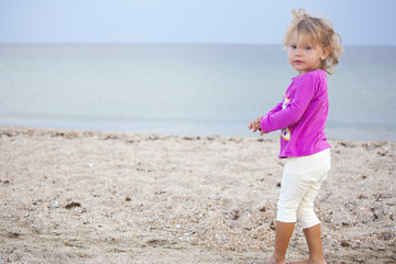 Fototapeta na wymiar Tanned girl standing on the sand