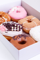 Colorful delicious donuts with glaze in a box on a wooden background