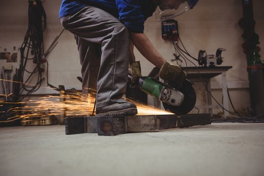 Welder cutting metal with grinder