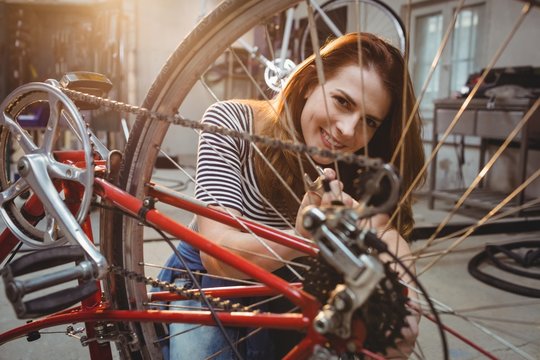 Woman repairing a red bicycle