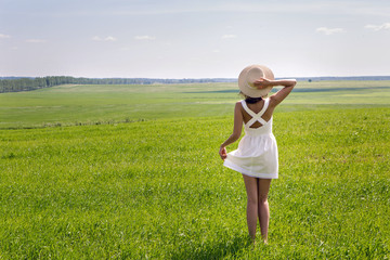 Naklejka na ściany i meble young girl with long dark hair standing on a green field