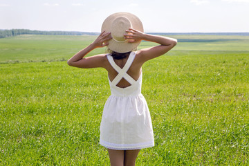 young girl with long dark hair standing on a green field