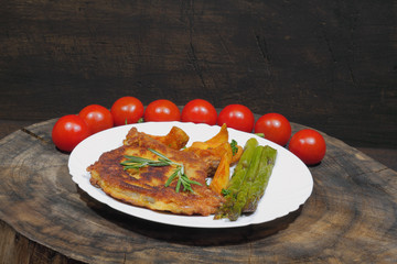 Cutlet with potato wedges, tomatoes, green asparagus, garnished