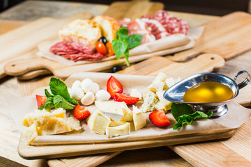 Delicious Cheese heaven. Cheese Mix, gouda cheese, cheese parmesan, feta cheese and strawberries with sauce on a wooden board