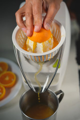 Hand holding orange fruit and making drink of fresh