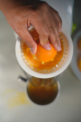 Hand holding orange fruit and making drink of fresh