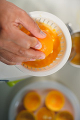 Hand holding orange fruit and making drink of fresh