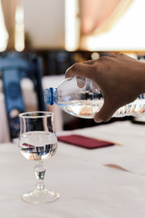 Closeup on pouring mineral water in the glass, restaurant background