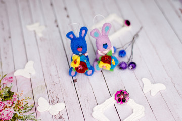 Two handmade knitted bunny rabbits and artistic decorations on wooden table background