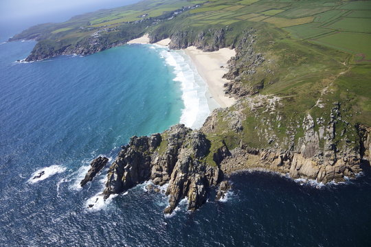 Aerial photo of Treen Cliff and Porthcurno beach looking west to the Minnack Theatre, West Penwith, Cornwall