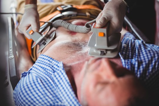 Injured man receiving help with a defibrillator