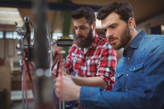 Mechanics repairing bicycle in workshop