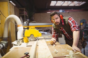 Carpenter marking on wooden plank with pencil in workshop