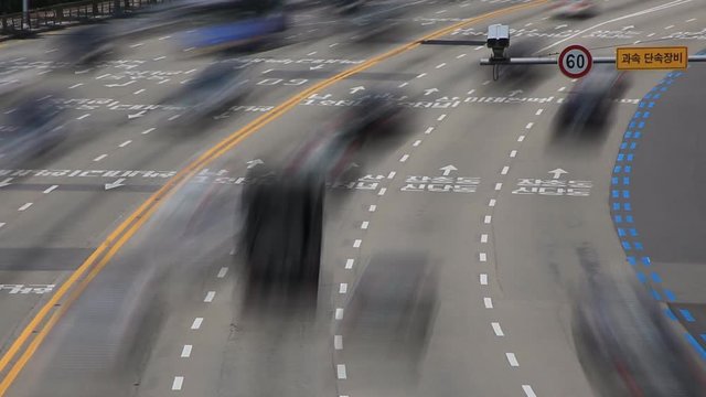 Time lapse of a speed camera against city traffic on road curved 