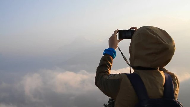 Asian woman watching the sunrise from the observatory of Poon Hill and taking photos of the beautiful panoramic view in Annapurna mountains in Nepal 