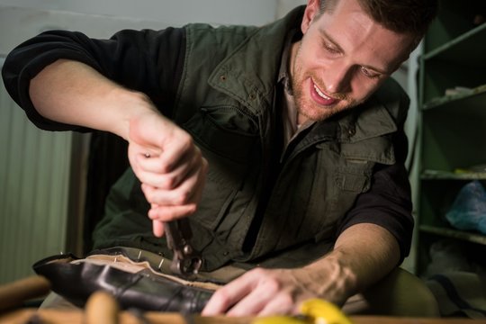 Portrait of a smiling cobbler repairing a shoe
