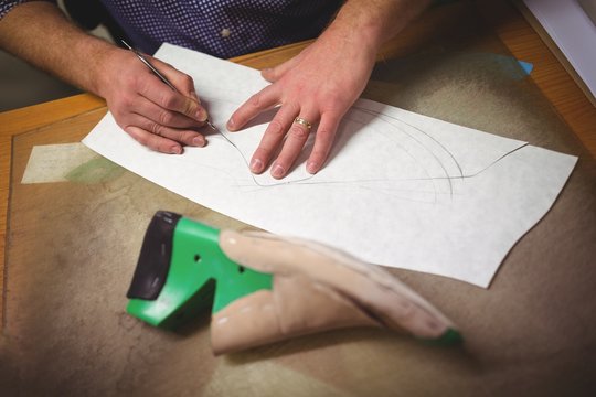 Cobbler making a design of shoe on paper