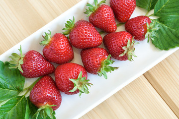 Strawberries with stems on a white platter

