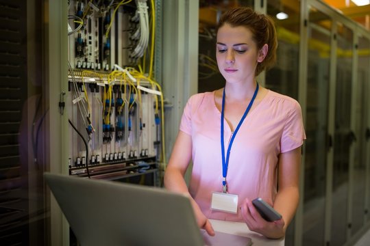 Technician using a laptop in server room