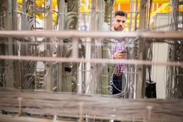 Technician using digital tablet while analyzing server