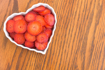 Sliced strawberries in a white heart shaped bowl
