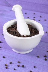 Black pepper in white mortar on purple boards