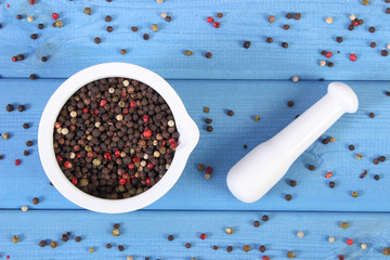 Colorful pepper in white mortar on blue boards