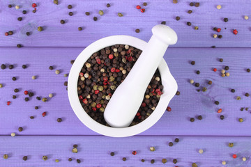 Colorful pepper in white mortar on purple boards