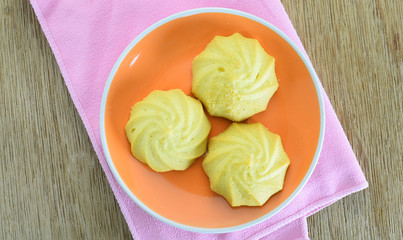 Butter cookies in orange dish on wooden table