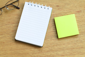 Yellow notes and white notebook on wooden background