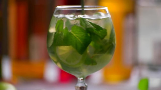 Green drink in a glass. Spoon rapidly mixing beverage. Juicy lime and fragrant mint. Chilled hugo cocktail.