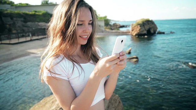 Smartphone woman sms texting using app on smart phone at beach sunset. Mixed