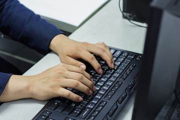 Businessman's hands on the keyboard of a silver laptop computer.