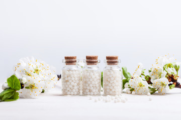 homeopathic pills with spring flowers on white background