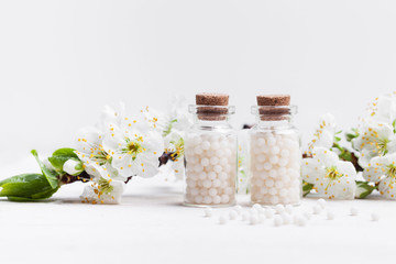 Fototapeta homeopathic pills with spring flowers on white background obraz