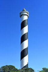 Obraz premium Black and white striped lighthouse on a cliffcoast. Beacon and copy space. 