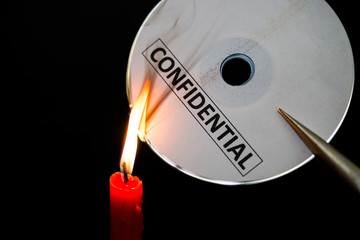 burning a confidential compact disc with candle in dark