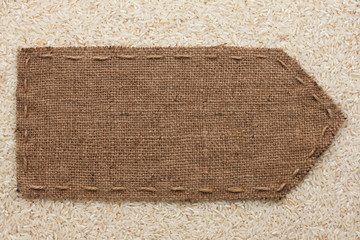 Fototapeta na wymiar Pointer of burlap lying on a rice background