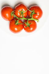 Washed ripe tomatoes group on plate on white background, vertica