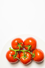 Washed ripe tomatoes group on plate on white background, vertica