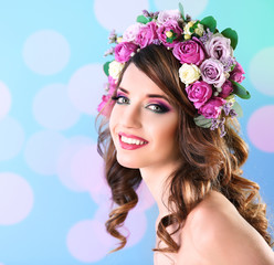 Beautiful young woman wearing floral headband on a blue festive background