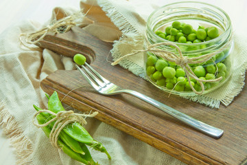 Green peas in glass plate on white wooden background