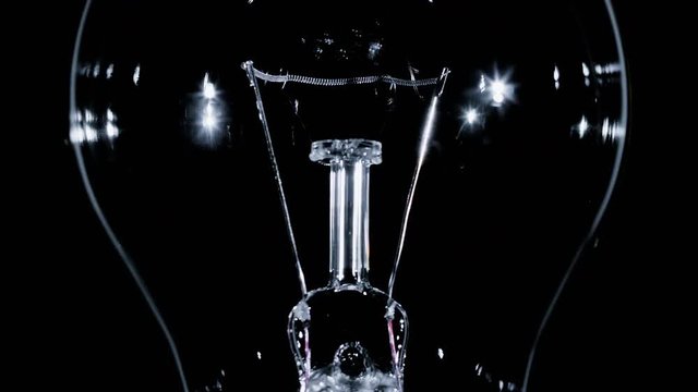 Edison lamp light bulb blinking over black background, macro view video, looped