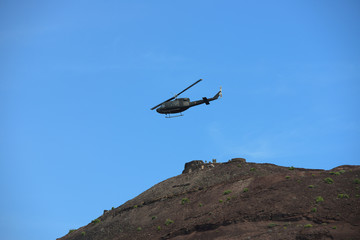 Naklejka na ściany i meble Military helicopter fly over a hill
