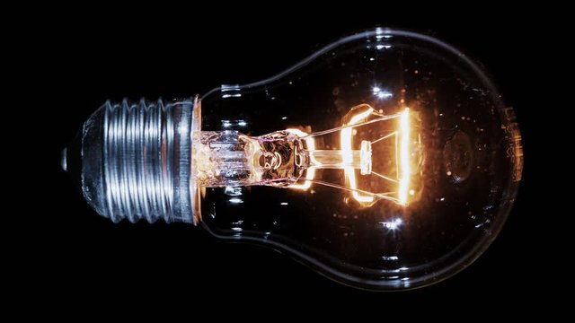 Edison lamp light bulb blinking over black background, macro view video