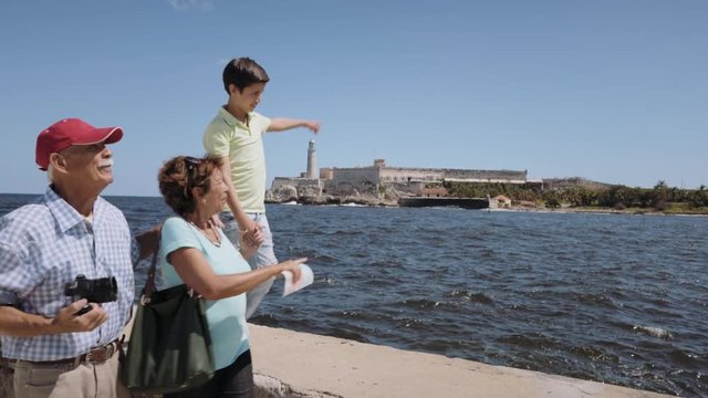 Happy tourists on holidays, during vacation journey. Hispanic people traveling in Havana, Cuba. Grandpa, grandma and grandson having fun near the sea. Family trip, old man, woman, boy walking together
