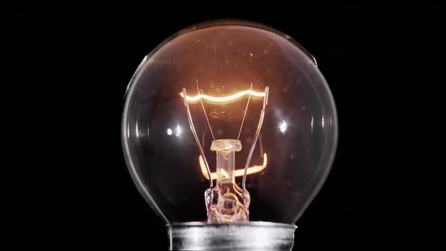 Edison lamp light bulb blinking over black background, macro view video, looped