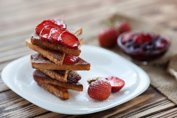 Toasts with cutted and fresh strawberry with sour cream and berry jam on wooden backcround