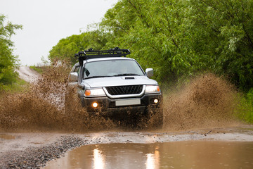 Obraz na płótnie Canvas Mitsubishi Pajero Sport moving by water making lots of splashes