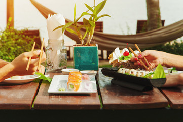 Two girls have a dinner with japanese sushi roll at the beach